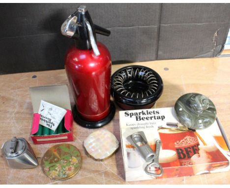 A vintage Colibri table lighter, a vintage red soda siphon with equipment, two vintage ladies' compacts, various bottle opene