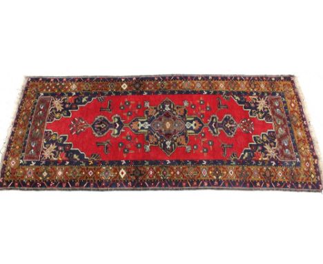 A hand-knotted red ground Tabriz carpet, blue spandrels with gold and red multi-border, 120 x 285cm.