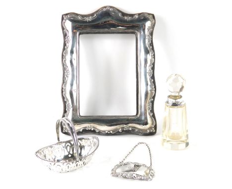 A silver photograph frame, silver gin decanter label, miniature silver basket, and a cut glass and silver rimmed scent bottle
