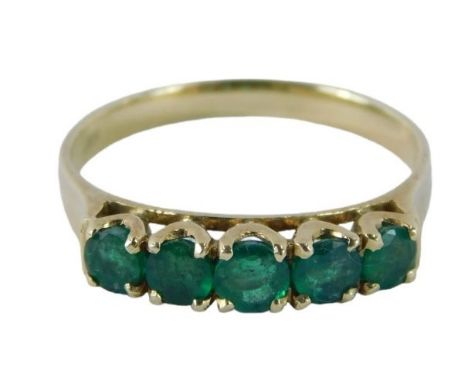 An emerald set dress ring, set with five round brilliant cut emeralds each in claw setting on a yellow metal band stamped 585