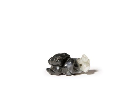 A CHINESE BLACK AND WHITE JADE CARVING OF A DOG AND A PUPPY LATE QING DYNASTY The recumbent mother with her large tail curlin