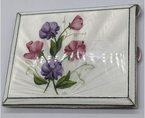 A silver guilloche enamel compact depicting flowers, the rear side with an engine turned finish, the gilt interior hallmarked