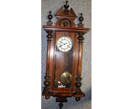A Vienna wall clock, white ceramic dial, original key and pendulum, classical head carving to pediment. Height 88cm.  Collect