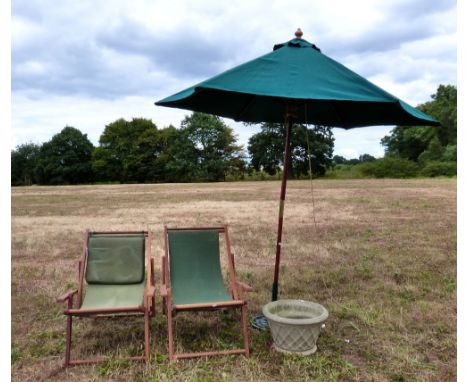 A wrought iron parasol stand and parasol, two deck chairs and a stone composite planter..    