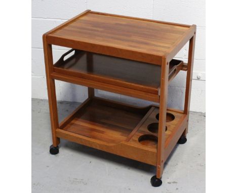 A retro teak trolley with three shelves, central shelf with lift-out butler's tray, above lower shelf with three apertures fo