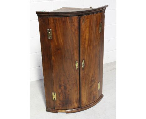 A late George III mahogany two-door wall-hanging bow-fronted corner cupboard with H-shaped brass hinges, height 103cm.