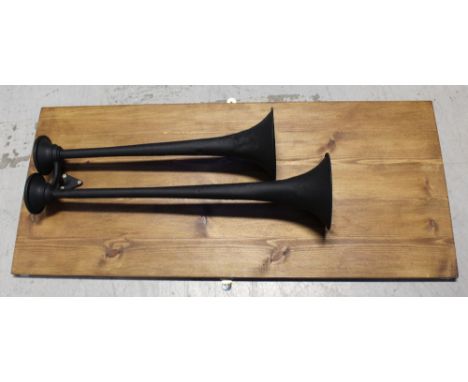 Two vintage c1920s car horns, painted black and mounted on a rectangular board, as an artwork, 114 x 50cm.
