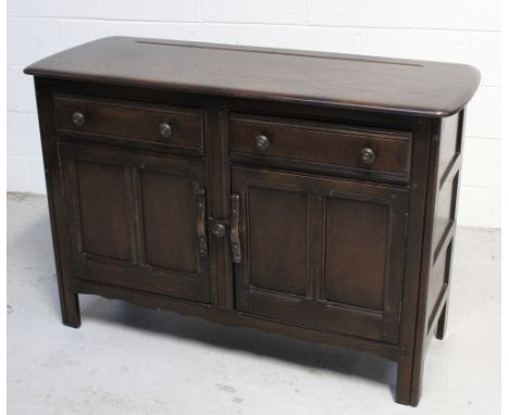 An Ercol 'Old Colonial' style sideboard of small proportions, two frieze drawers over two panelled cupboard doors, on block s