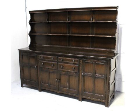 An Ercol 'Old Colonial' dresser, two plate racks above four central frieze drawers, two panelled cupboards and panelled cupbo