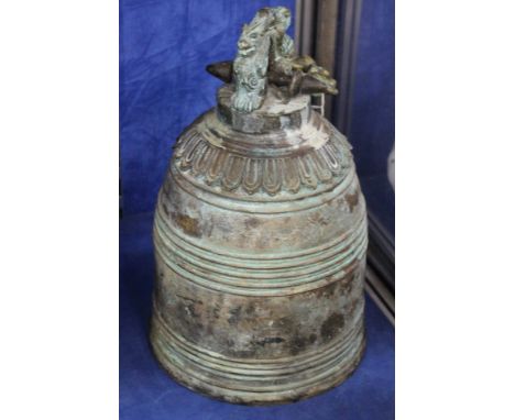 A Chinese bronze bell moulded with dragon faces, 35cm high, 