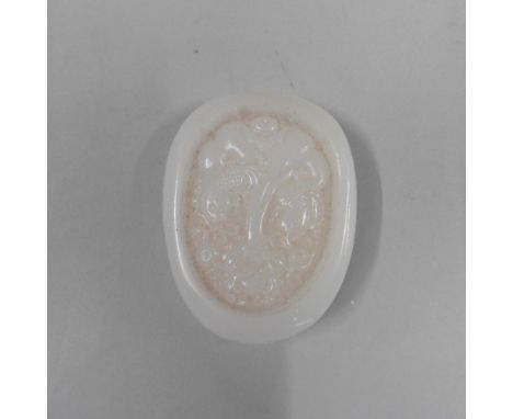 A white jade tablet of oval form, carved with two carp in rough water, 2.5in x 2in.