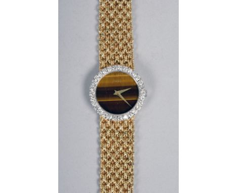 A Piaget ladies wrist watch with a tigers eye face surrounded by an outer band of cut diamonds and with an 18ct gold plaited 
