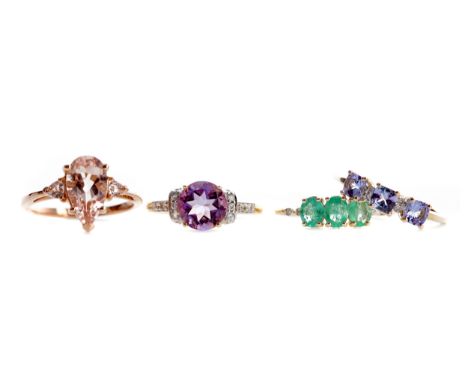 FOUR GEM SET RINGS, including a peach gem set three stone ring, in nine carat rose gold, size N, a purple gem set and diamond