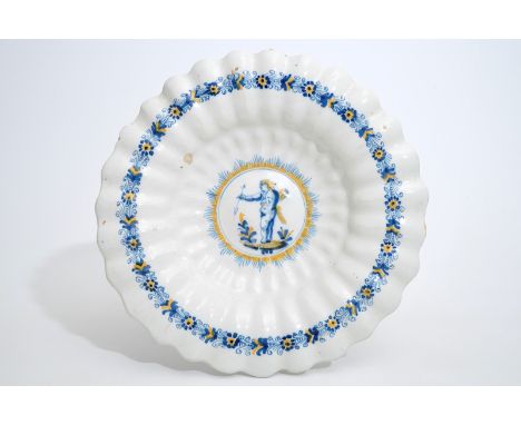 A Dutch Delftware gadrooned dish with a putto in blue and yellow, Haarlem, 17th C. Dia.: 33 cm  Condition reports and high re