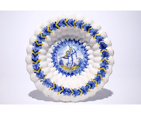 A Dutch Delftware gadrooned dish with a putto in blue and yellow, Haarlem, 17th C. Dia.: 33,5 cm  Condition reports and high 