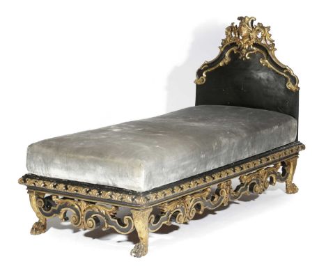 AN ITALIAN EBONISED AND GILTWOOD DAY BED 19TH CENTURYcarved with leaves and scrolls, the headboard with a female mask surmoun