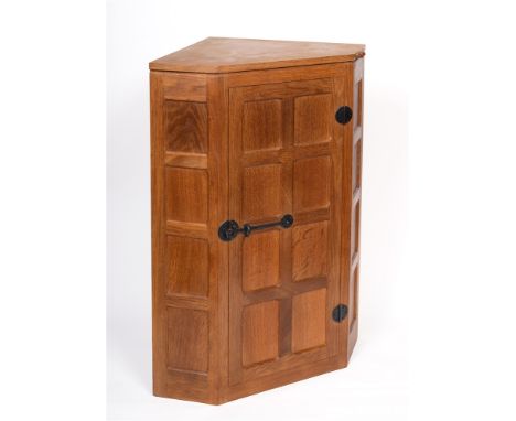 ROBERT 'MOUSEMAN' THOMPSON  a hanging oak corner cabinet, with wrought iron hinges and latch, the eight panelled door opening