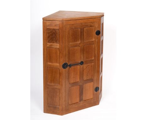 ROBERT 'MOUSEMAN' THOMPSON  a hanging oak corner cabinet, with wrought iron hinges and latch, the eight panelled door opening