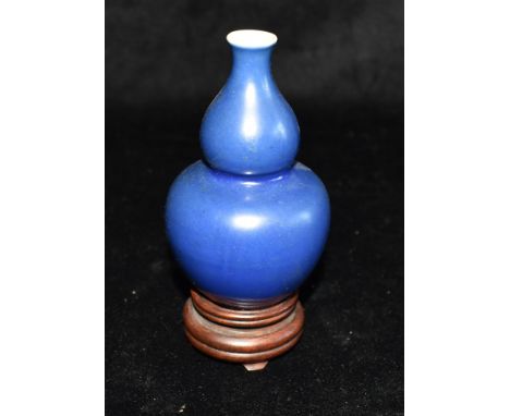 A SMALL CHINESE DOUBLE GOURD SHAPED PORCELAIN VASE with underglaze blue double circle mark to base, on hardwood stand, the va