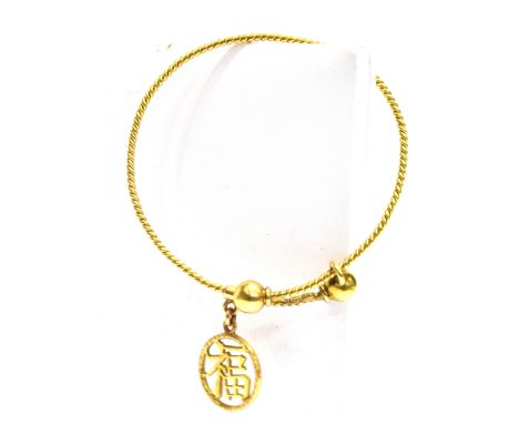 AN 18CT GOLD BABY'S BANGLE  with Chinese symbol circular pendant, the barley twist wirework bangle with bead ends, applied st