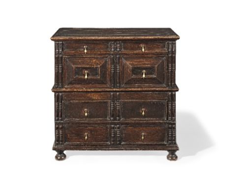 A 17th century oak chest of drawersIn two halves, with panelled drawer fronts flanked by bobbin turned mouldings on later bun