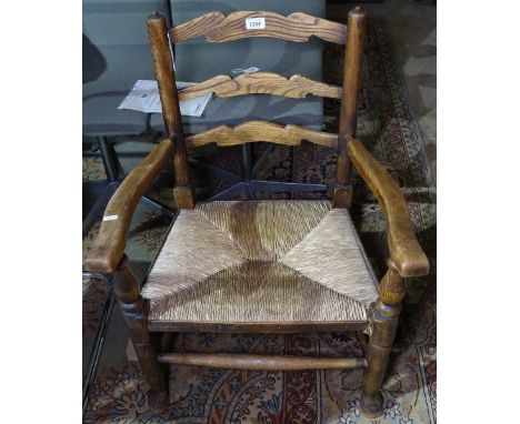 A small Antique ladder-back rush-seated elbow chair