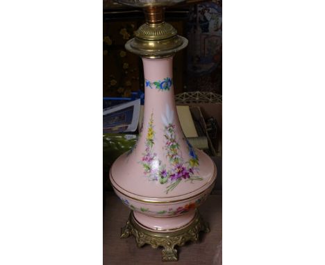 A 19th century porcelain and brass oil lamp, with hand painted floral decoration, cut glass font, and moulded pink glass shad