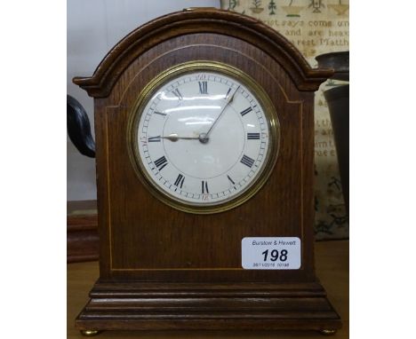 An oak-cased dome-top mantel clock with brass carrying handle, height 8.5"