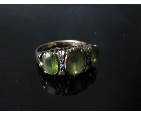 A 9ct gold ring with three oval peridots, the central stone flanked by three diamonds. Size N/O, 4.1g 