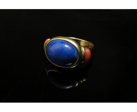 A gold ring, unmarked, set with oval lapis lazuli, flanked by coral in rubover setting, shank repaired. Size Q/R, 7.3g 