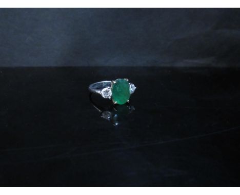 A 20th Century gold emerald and diamond ring the central oval emerald 11mm x 9mm flanked by 0.25ct approx diamonds, shank sta