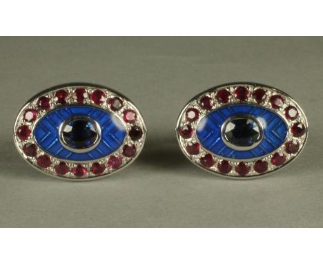 A PAIR OF RUBY SET CUFFLINKS, the oval panels centred by a collet set stone on a herringbone blue guilloche enamel ground wit