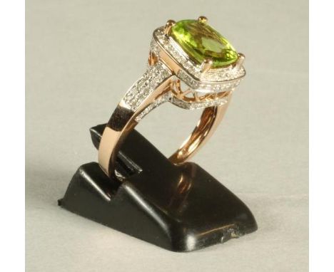 A PERIDOT AND DIAMOND DRESS RING, the cushion cut peridot of approximately 3.20cts, claw set to a border of millegrain set br