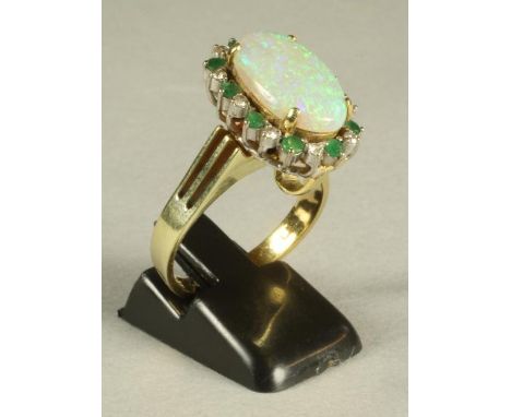 AN OPAL, EMERALD AND DIAMOND COCKTAIL RING/PENDANT, the oval cabochon polished opal claw set to an open border of ten each al