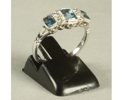 AN ART DECO STYLE AQUAMARINE AND DIAMOND RING, the three oblong cut aquamarines open back collet set and interspersed with tw