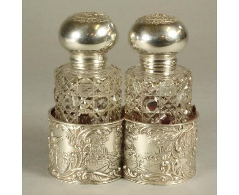 A PAIR OF LATE VICTORIAN GLASS TOILET BOTTLES of plain cylindrical form with hobnail cutting, the silver mounts and hinged co