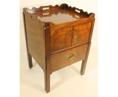 A GEORGIAN MAHOGANY NIGHT COMMODE of square tray topped form, the waved gallery pierced with loop handles, two doors over a p