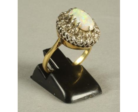 AN OPAL AND DIAMOND CLUSTER RING, the oval cabochon polished opal claw set to a border of fourteen small diamonds and a plain