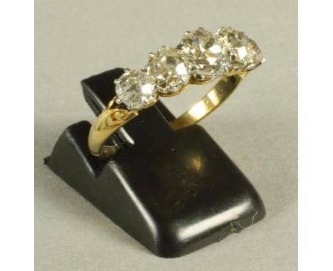 A FIVE STONE DIAMOND RING, the central brilliant cut claw set stone of approximately 0.6cts flanked by similar smaller stones