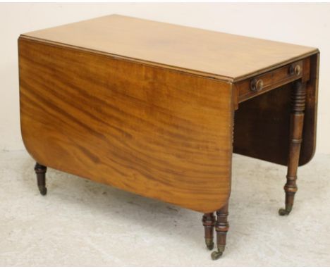 A REGENCY MAHOGANY DROP LEAF DINING TABLE of rounded oblong form with reeded edged top, frieze drawer with turned wood handle