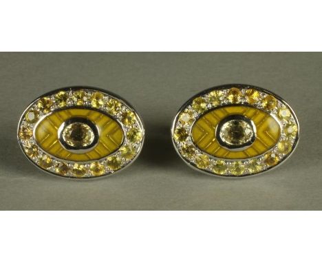 A PAIR OF YELLOW SAPPHIRE SET CUFFLINKS, the oval panels centred by a collet set stone on a yellow herringbone guilloche enam