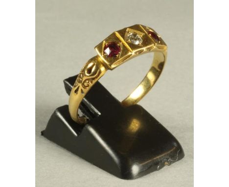 A VICTORIAN 18CT GOLD RING, gypsy set with an old brilliant cut diamond flanked by two facet cut rubies to scroll chased shou