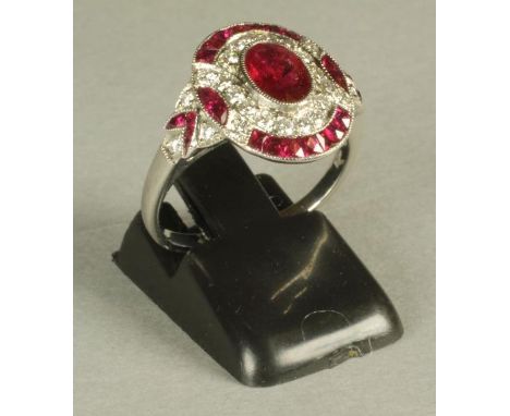 AN ART DECO STYLE RUBY AND DIAMOND PLAQUE RING, the oval panel centrally set with an oval facet cut ruby, collet set to a bor