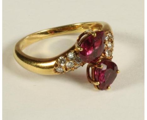 A RUBY AND DIAMOND RING, the two facet cut tear shaped rubies claw set in a crossover type setting, the shoulders each pave s