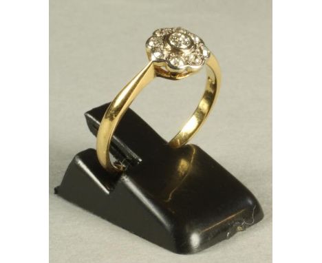 A DIAMOND CLUSTER RING, the central brilliant cut stone within a border of eight similar smaller stones to a plain 18ct gold 