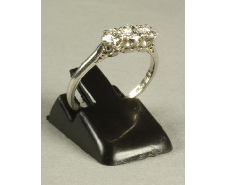 A THREE STONE DIAMOND RING, the brilliant cut stones claw set to a plain platinum shank, size M 1/2