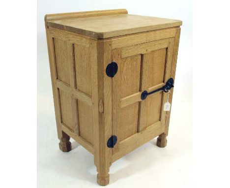 A ROBERT THOMPSON ADZED OAK BEDSIDE CABINET, of multi panelled oblong form, the moulded edged top with ledge back, door below