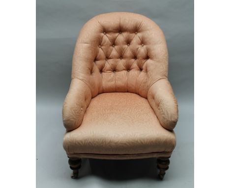 A LATE 19TH CENTURY UPHOLSTERED BUTTON BACKED LOW-SEATED ARMCHAIR, on show wood legs with white ceramic castors below, 89cm t