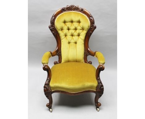 A 19TH CENTURY CARVED SHOW WOOD FRAMED DEEP SEATED ARMCHAIR, having old gold velour upholstered button back seat and arm pads