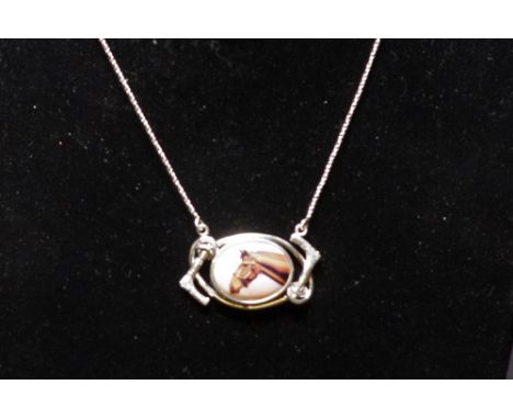 A silver pendant necklace, the pendant inset with an enamel plaque depicting a thoroughbred horse, the mount in the form of r